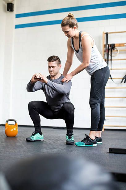 Full length shot of female personal trainer guiding man doing_
